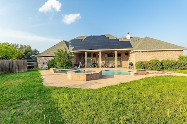 rear view of property with a pool with hot tub, a patio, a lawn, and solar panels