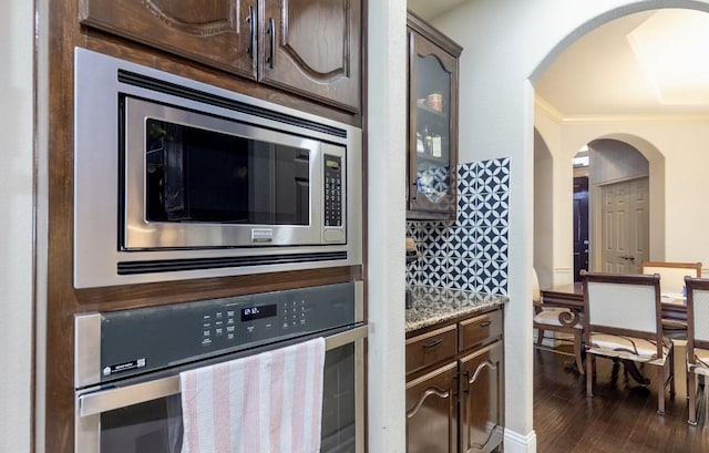 kitchen featuring appliances with stainless steel finishes, dark hardwood / wood-style flooring, dark brown cabinets, and light stone countertops