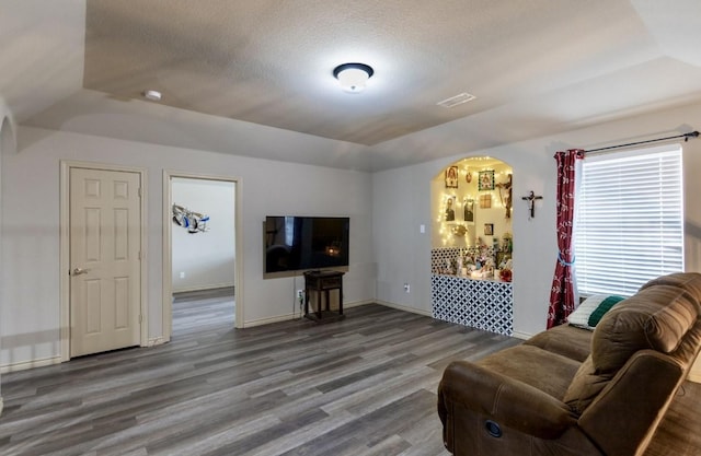 living room featuring a textured ceiling, hardwood / wood-style flooring, and lofted ceiling