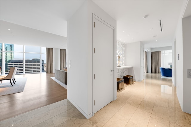 hall with a wall of windows and light tile patterned floors