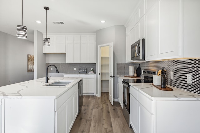 kitchen featuring appliances with stainless steel finishes, a center island with sink, pendant lighting, sink, and white cabinetry