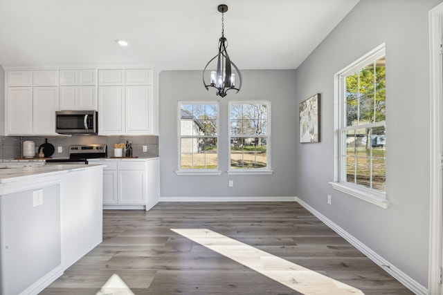 kitchen with appliances with stainless steel finishes, tasteful backsplash, a wealth of natural light, and white cabinets