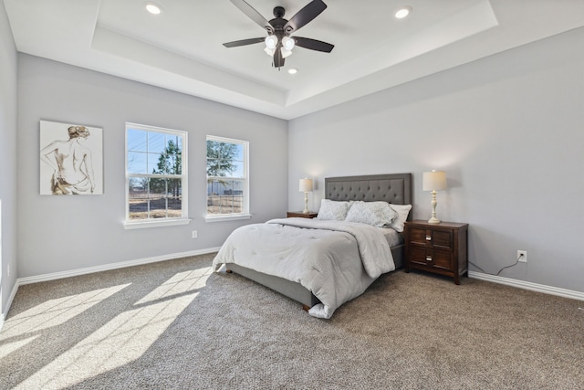 bedroom featuring a raised ceiling, ceiling fan, and carpet floors