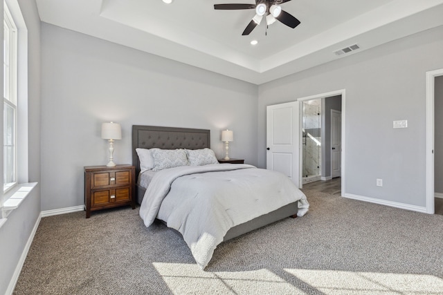 carpeted bedroom with a raised ceiling and ceiling fan