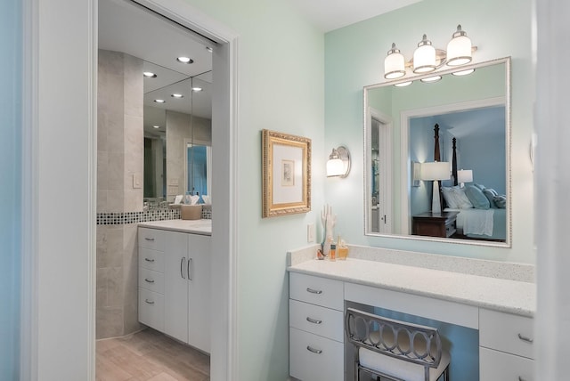 bathroom with wood finished floors, vanity, and recessed lighting