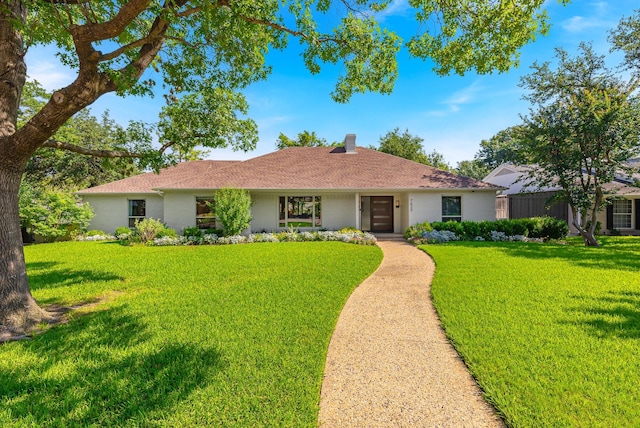 ranch-style home with a front yard and a chimney