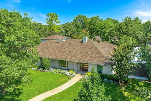 single story home featuring brick siding, roof with shingles, a front yard, and fence