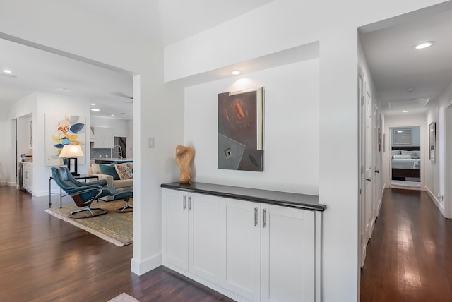 hall featuring dark wood-type flooring, recessed lighting, and baseboards