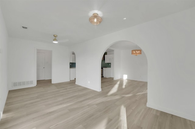 spare room with light wood-type flooring, arched walkways, visible vents, and ceiling fan