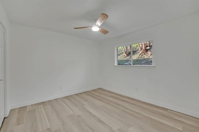 spare room with light wood finished floors, baseboards, and a ceiling fan