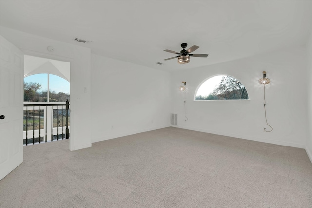 empty room featuring a ceiling fan, visible vents, and light colored carpet