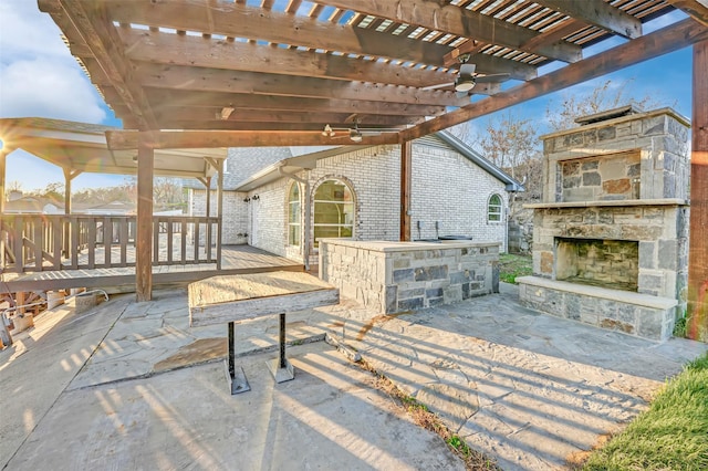 view of patio / terrace with an outdoor stone fireplace, an outdoor bar, a wooden deck, and a pergola