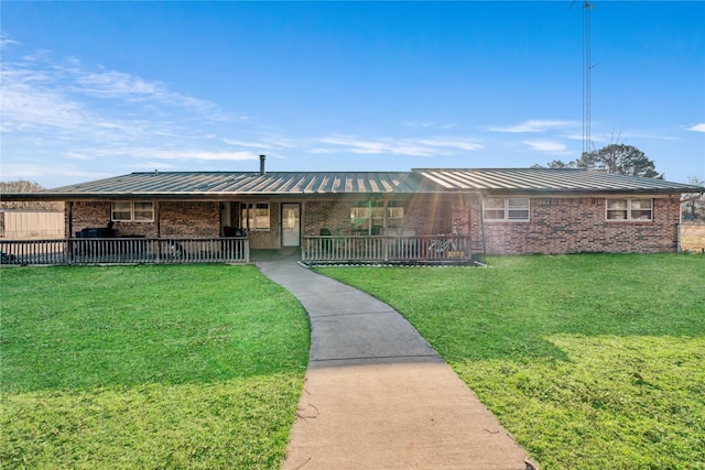 ranch-style house featuring a standing seam roof, a front yard, metal roof, and brick siding