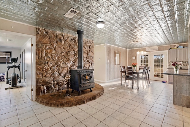 interior space featuring light tile patterned floors, visible vents, an ornate ceiling, and a wood stove