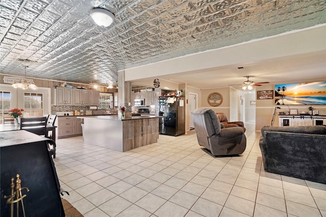 kitchen featuring light tile patterned floors, open floor plan, freestanding refrigerator, stainless steel microwave, and an ornate ceiling