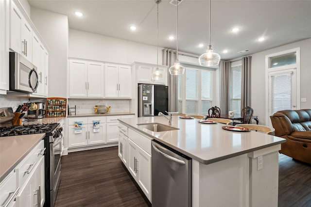 kitchen featuring dark wood-style floors, stainless steel appliances, an island with sink, and a sink