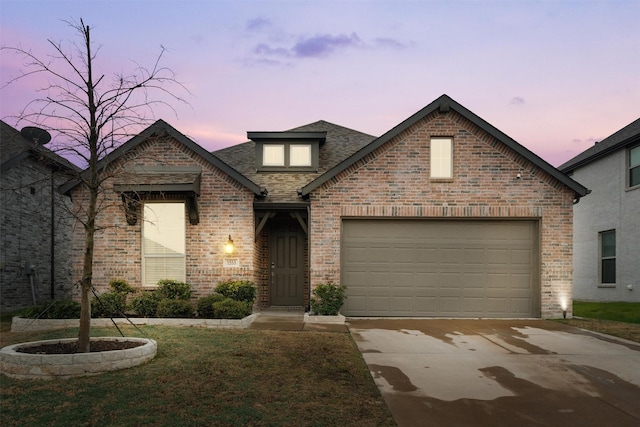 view of front of property with a yard, driveway, brick siding, and an attached garage