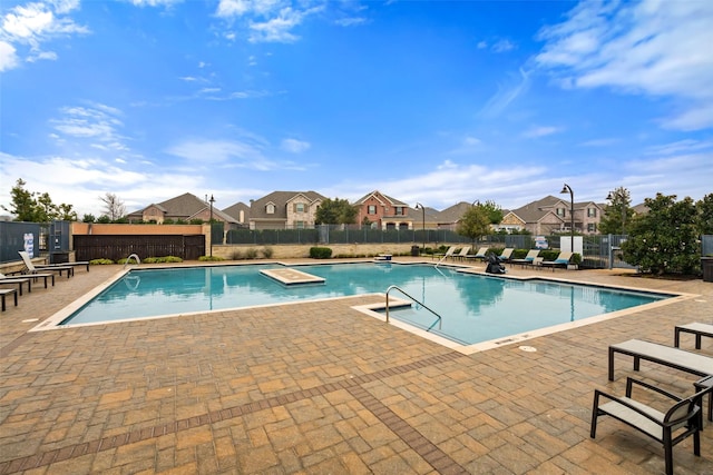 pool with a patio area, fence, and a residential view