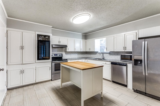 kitchen featuring white cabinetry, a center island, sink, appliances with stainless steel finishes, and wooden counters