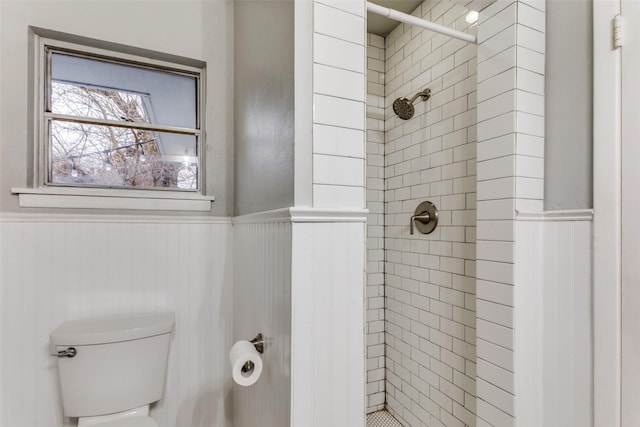 bathroom featuring tiled shower and toilet