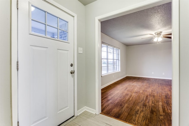 foyer entrance featuring ceiling fan, light hardwood / wood-style floors, and a textured ceiling