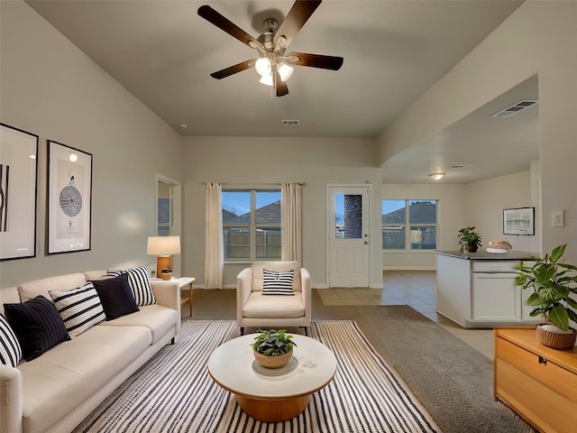 living area with ceiling fan, light tile patterned flooring, visible vents, and plenty of natural light