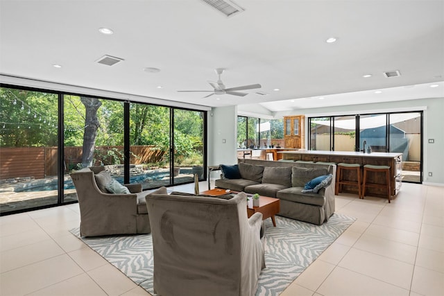 tiled living room featuring ceiling fan and expansive windows