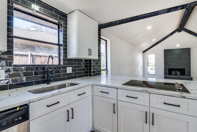 kitchen with light stone counters, black electric stovetop, a sink, white cabinetry, and dishwasher