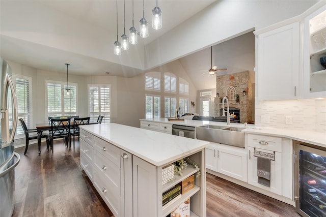 kitchen with pendant lighting, open shelves, white cabinets, a kitchen island, and beverage cooler