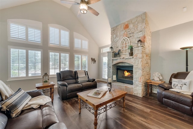 living area featuring high vaulted ceiling, a ceiling fan, dark wood-type flooring, and a stone fireplace