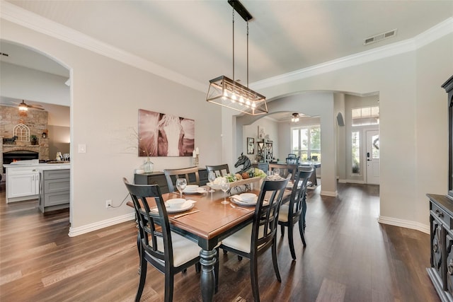 dining space with arched walkways, dark wood-style flooring, visible vents, and crown molding