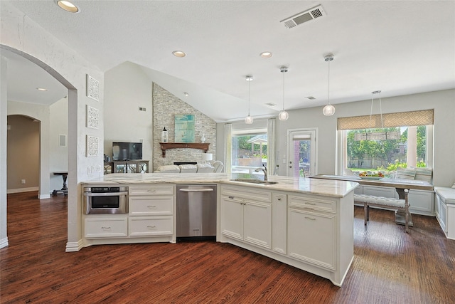 kitchen featuring stainless steel appliances, light stone counters, white cabinets, lofted ceiling, and decorative light fixtures