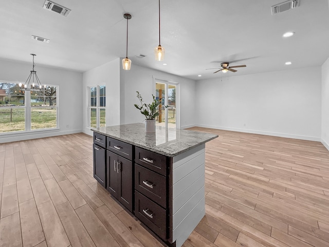 kitchen featuring light wood-type flooring, pendant lighting, light stone countertops, and a wealth of natural light