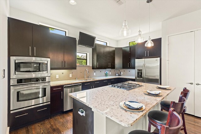 2123 Albany St, Dallas, TX 75201 - kitchen featuring hanging light fixtures, a kitchen island, light stone countertops, sink, and appliances with stainless steel finishes