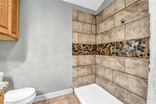 full bathroom featuring baseboards, tiled shower, toilet, and tile patterned floors