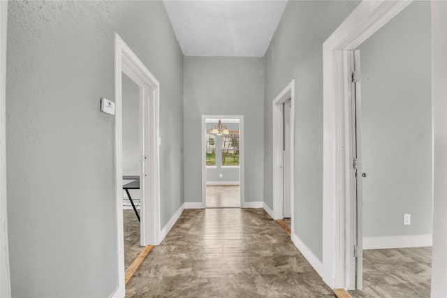 hall with a chandelier and baseboards