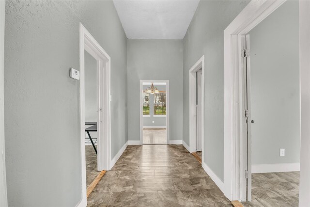 hall with baseboards and a notable chandelier