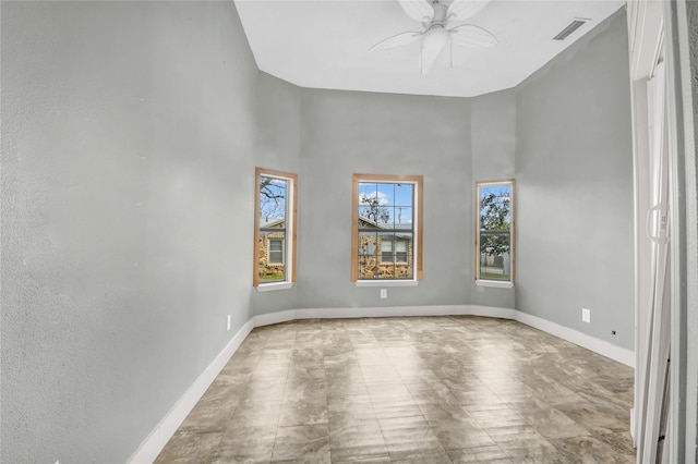 empty room with ceiling fan, a towering ceiling, baseboards, and visible vents