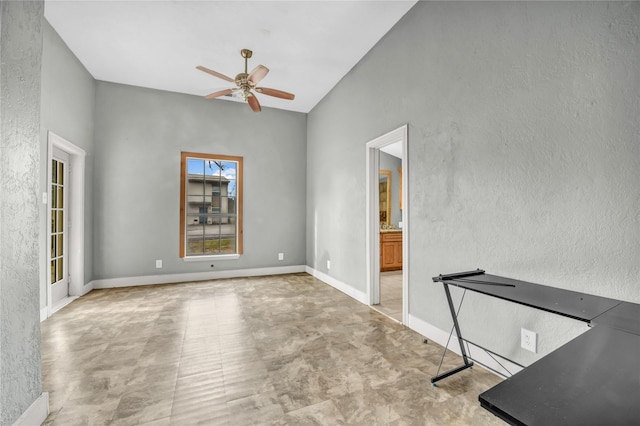 empty room featuring baseboards, ceiling fan, a textured wall, and vaulted ceiling