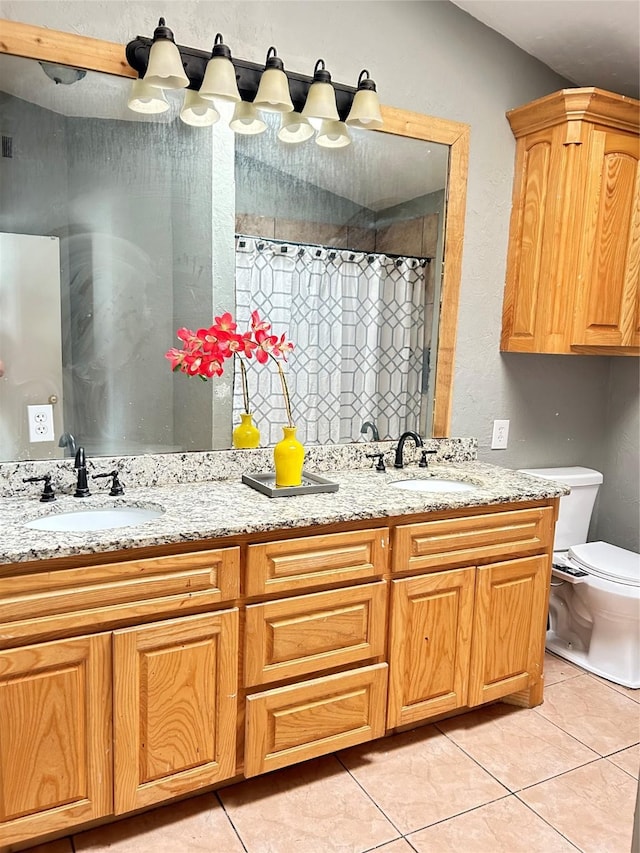bathroom with toilet, tile patterned flooring, and a sink