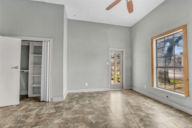 unfurnished bedroom featuring multiple windows, ceiling fan, and baseboards