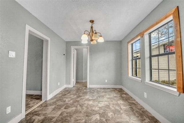 unfurnished dining area with an inviting chandelier and baseboards