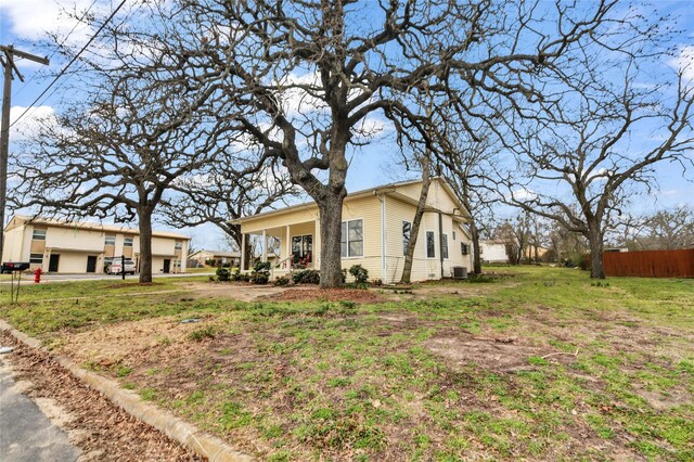 view of home's exterior featuring a yard, cooling unit, covered porch, and fence