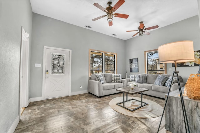 living area with baseboards, ceiling fan, and visible vents