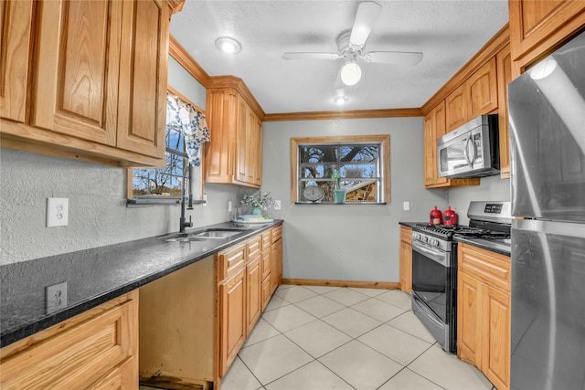 kitchen featuring light tile patterned floors, a sink, crown molding, ceiling fan, and appliances with stainless steel finishes