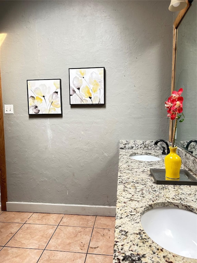full bath with a sink, double vanity, baseboards, and tile patterned floors