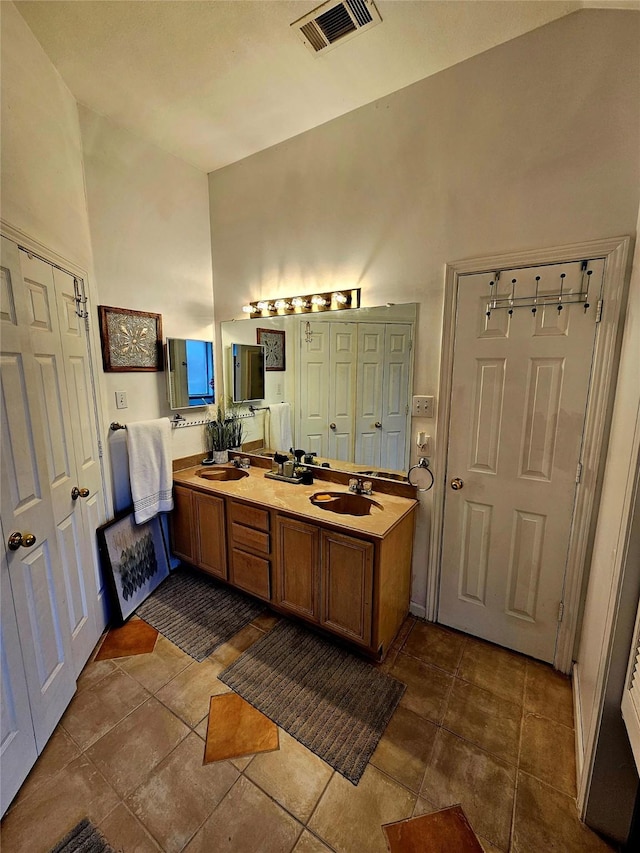 bathroom with vanity, tile patterned flooring, and a towering ceiling