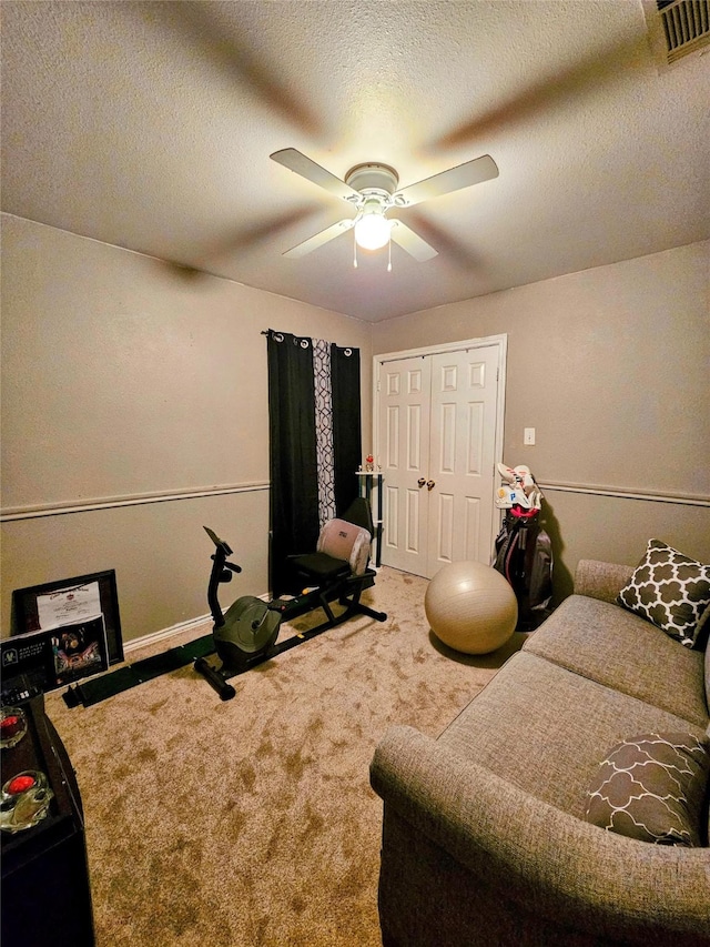 exercise area with ceiling fan, carpet flooring, and a textured ceiling