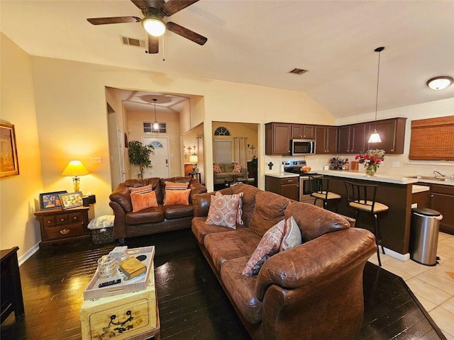 tiled living room featuring lofted ceiling, ceiling fan, and sink