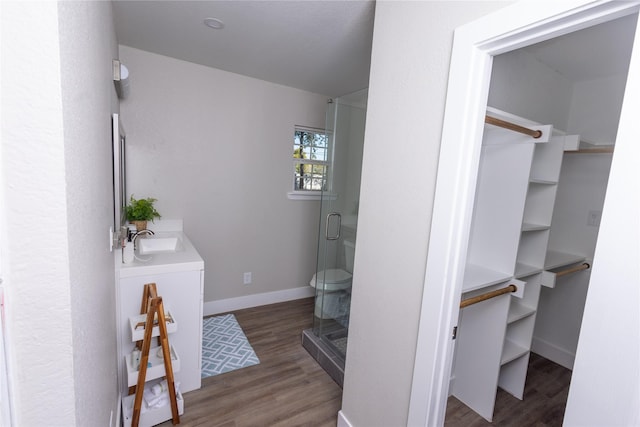 full bathroom with vanity, a shower stall, baseboards, and wood finished floors